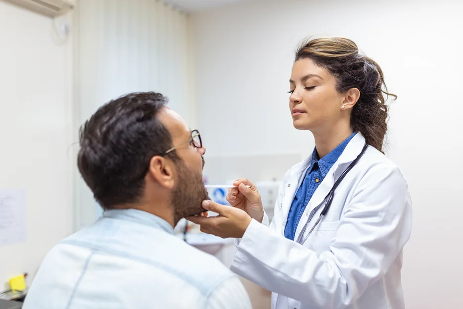 doctor uses tongue depressor to examine her patient