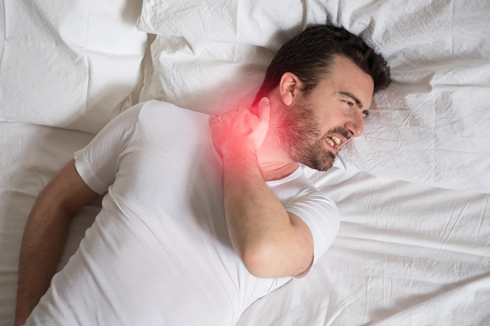 a man lying on the bed suffers neck pain