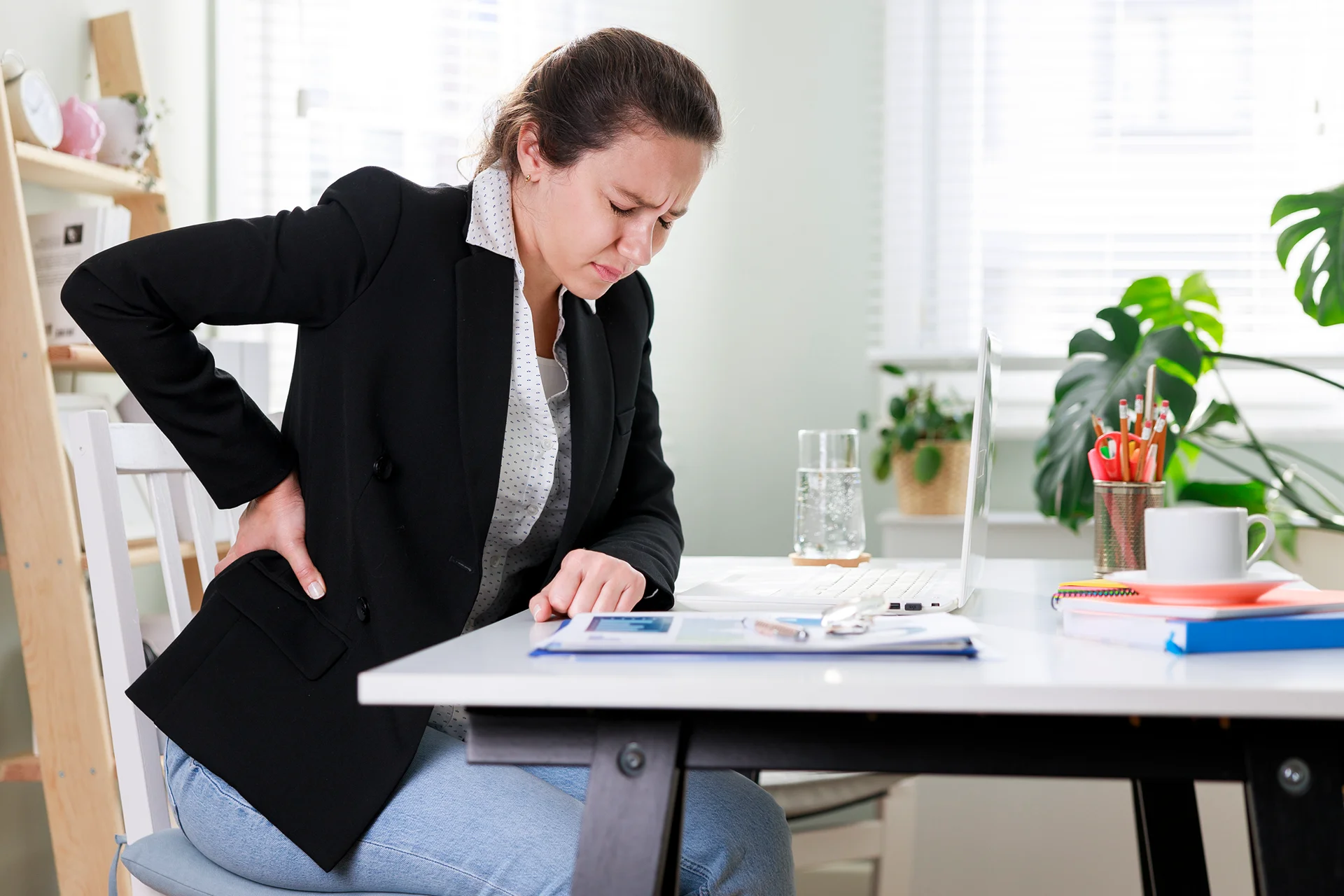 a woman suffers back pain at work