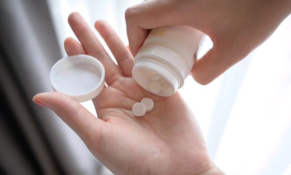 a woman pours pills on her hand