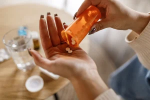 a woman pours white pills into her hand