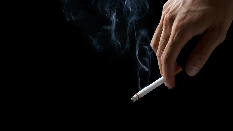 a closeup of a hand holding a lighted cigarette