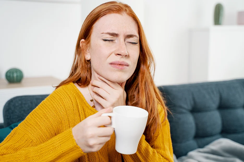 a woman holding a glass of water while enduring her neck pain