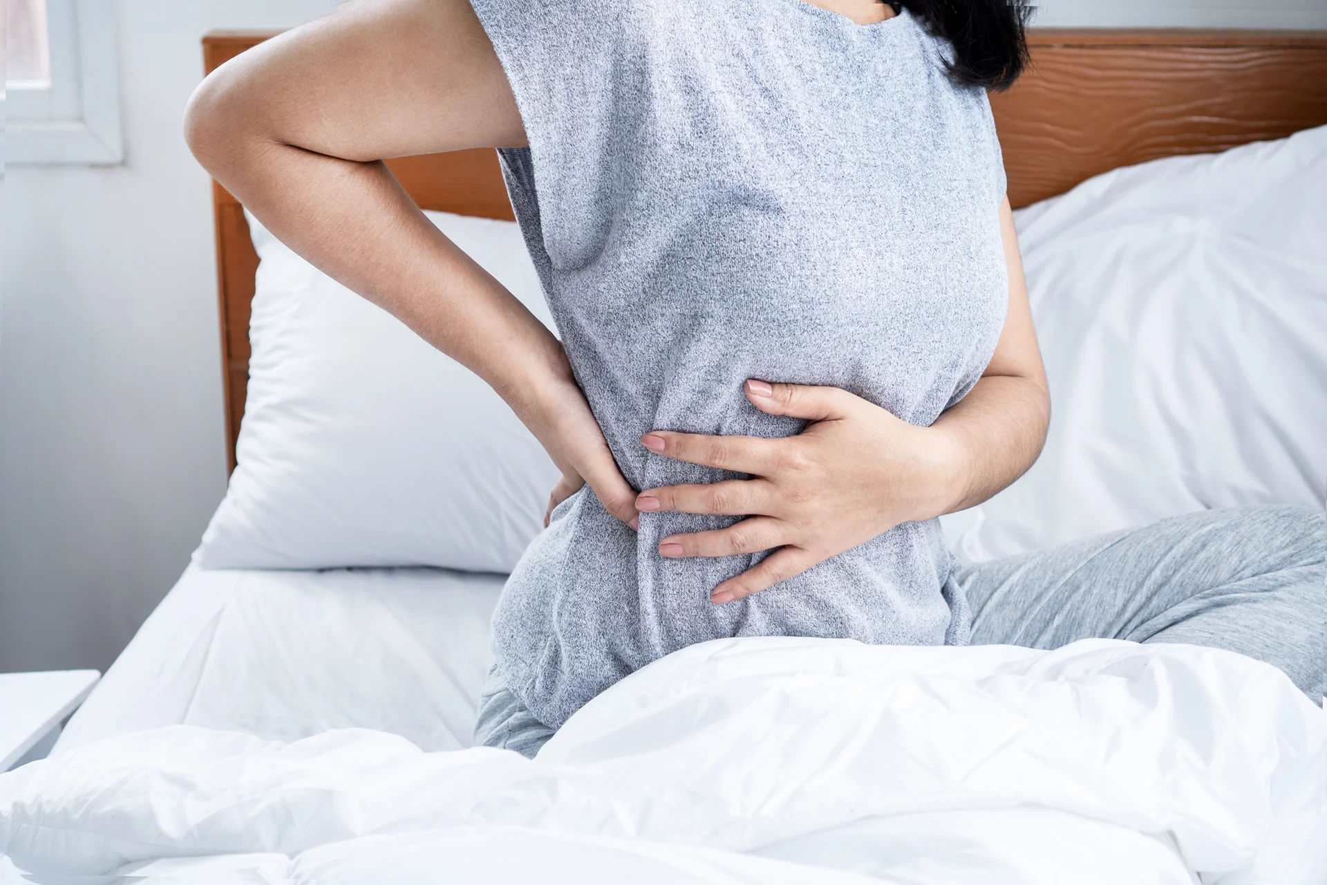 a woman suffering from low back pain after sleeping