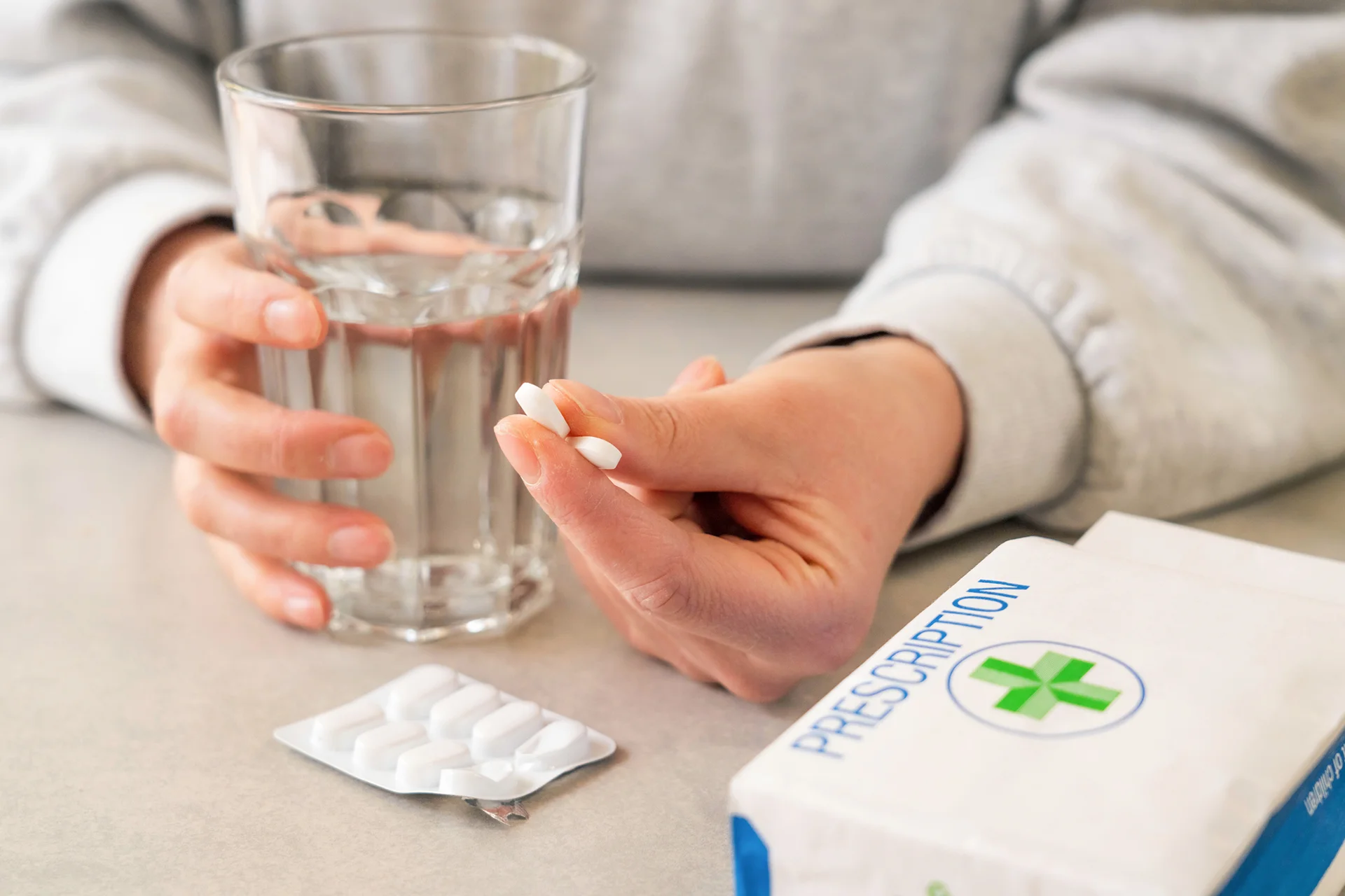 a woman is holding pills and a glass of water
